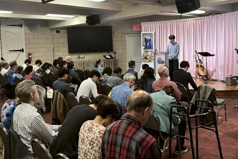 A congregation seated in a hall, seen from the back of the room.
